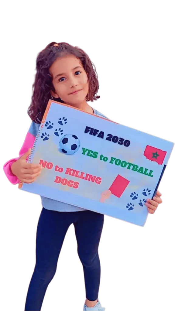 A young girl with dark hair and eyes smiles at the camera, holding a sign saying 'Fifa 2030, Yes to Football, No to Killing Dogs'